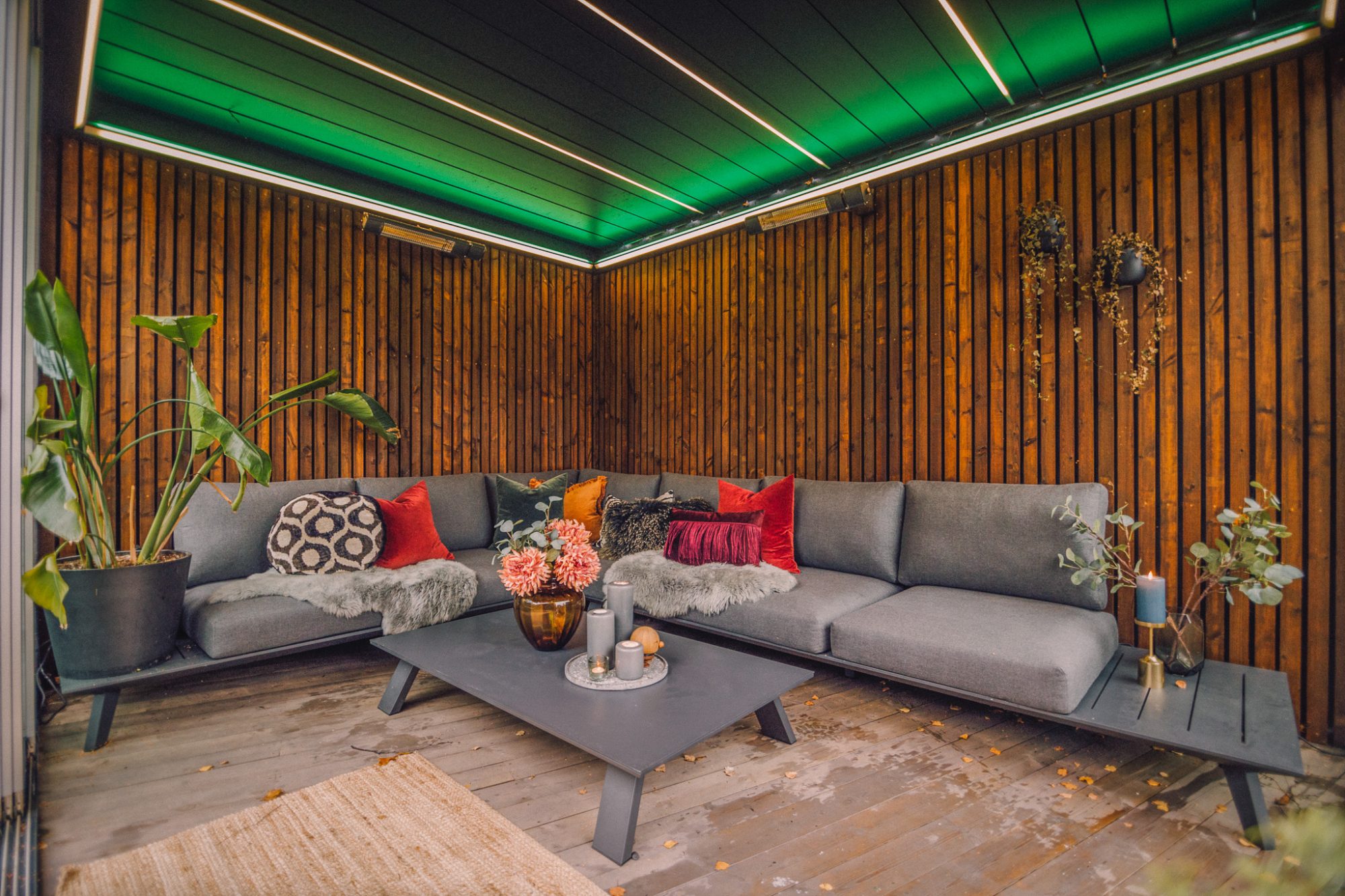 Komfortable utemøbler og planter inne i en solid og vakker utendørs pergola bygget av uteDESIGN