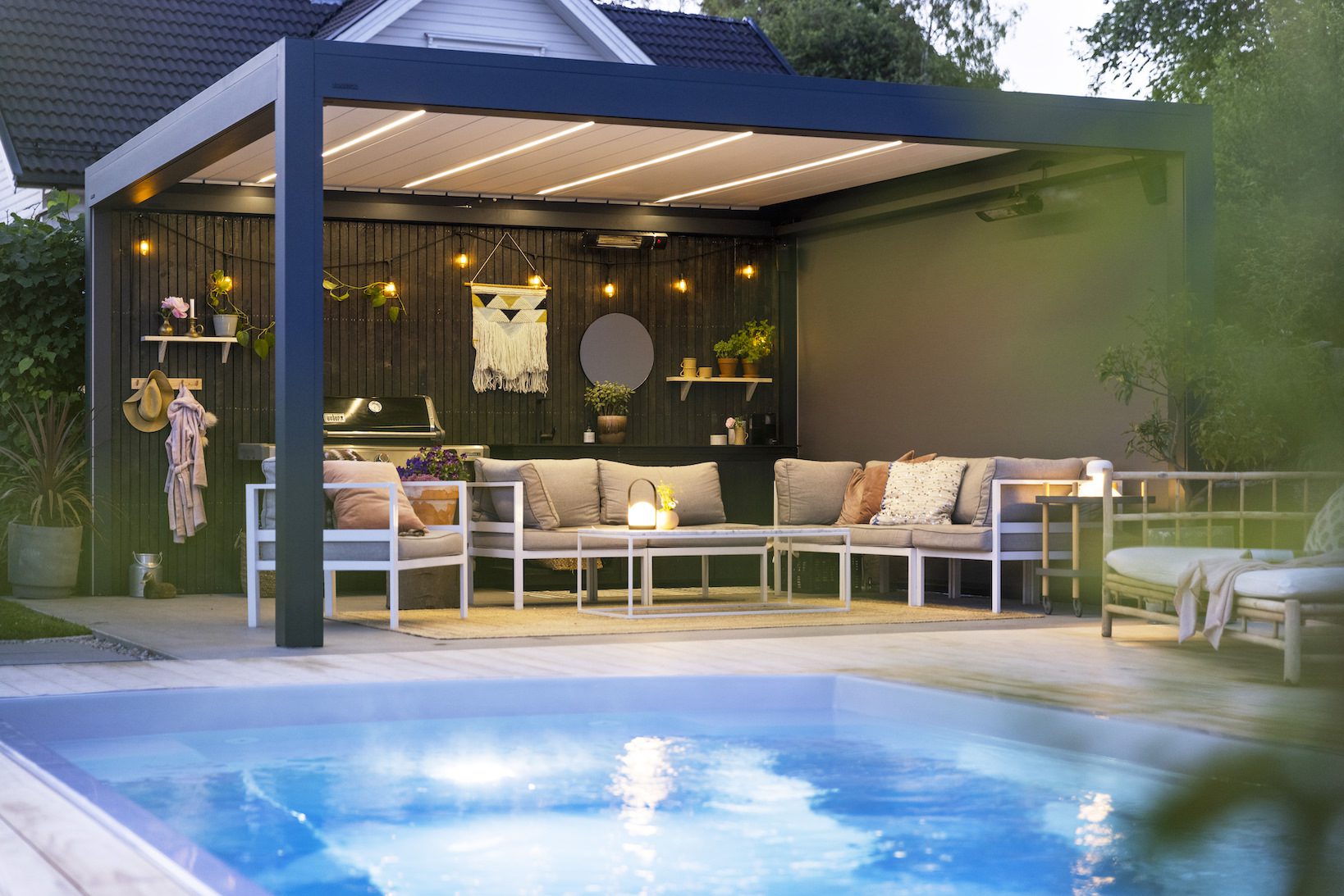 Uteplass med pergola i bakgården ved siden av bassenget, bygget av uteDESIGN