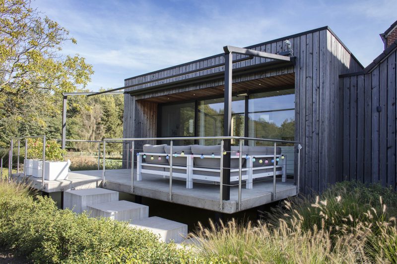 Bildet av et hus med pergolamarkise på utsiden. Markisen er tatt inn og under er det møbler på terrassen.