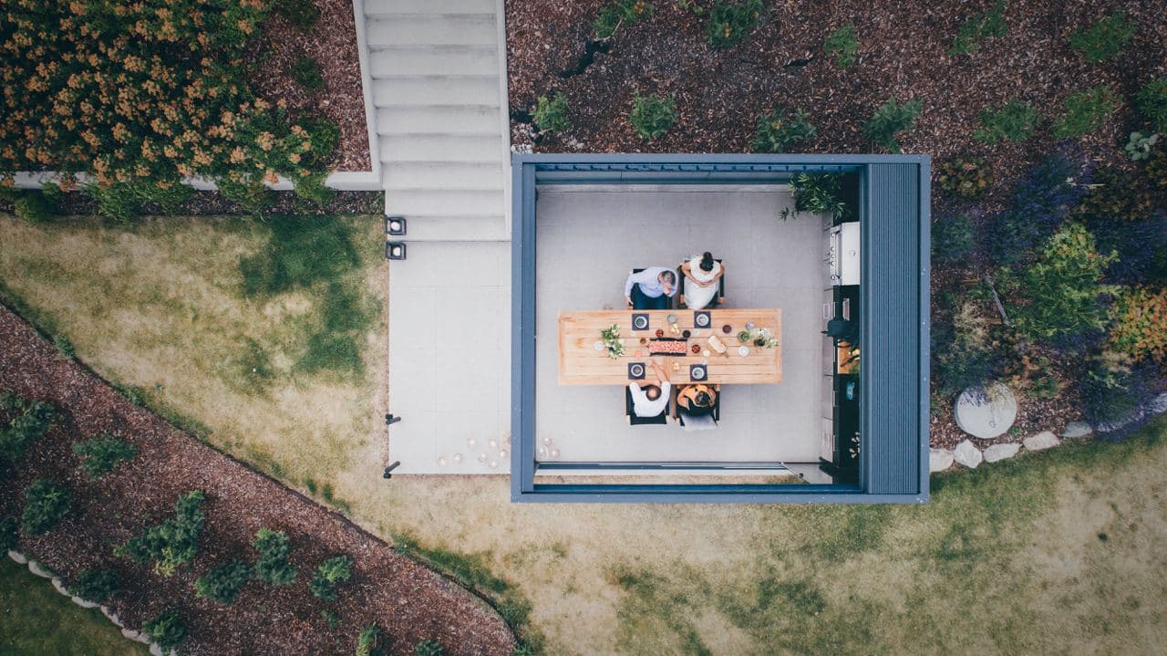 Brustor B600s drone Bildet ovenfra for en pergola med lamelltak. Lamellene er tatt til side slik at man ser menneskene inni.