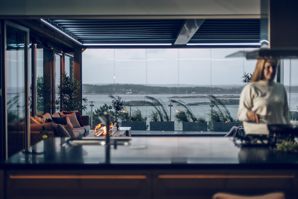 Bildet av en pergola med duk, på kveldstid med sjøutsikt.