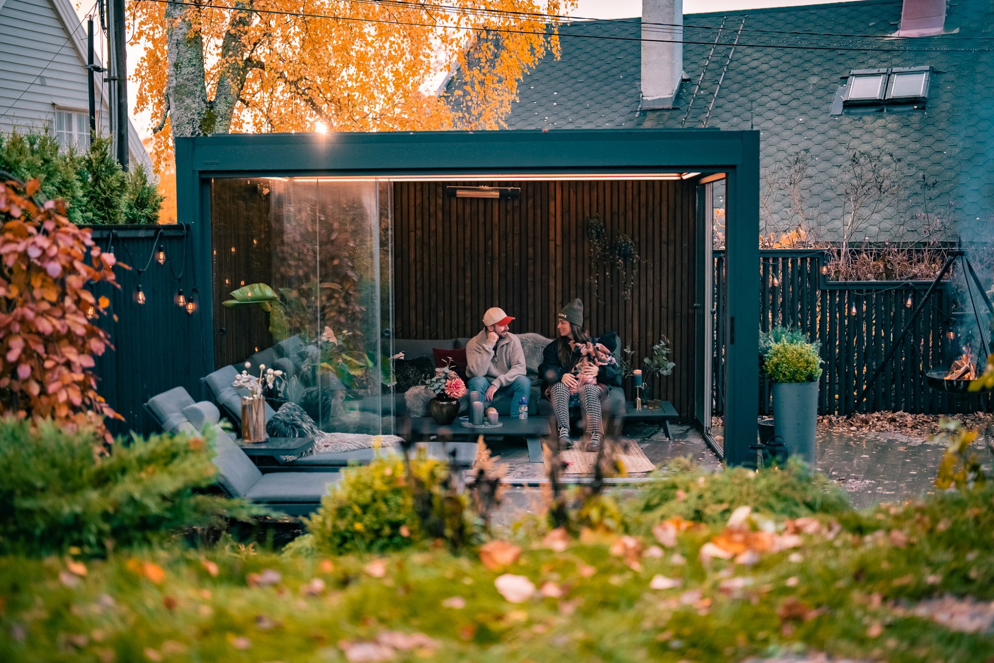 Pergola – utestue 2 En pergola med lameller i nydelig høst vær. Det sitter en familie inne i den.